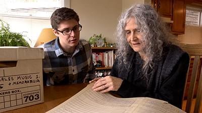 woman and young man looking at sheet music while seated at a table