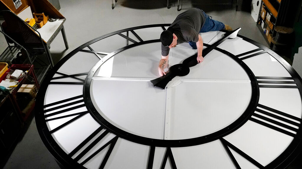 Electric Time technician Dan LaMoore puts a clock hand onto a 1000-lb., 12-foot diameter clock constructed for a resort in Vietnam, Tuesday, March 9, 2021, in Medfield, Mass.