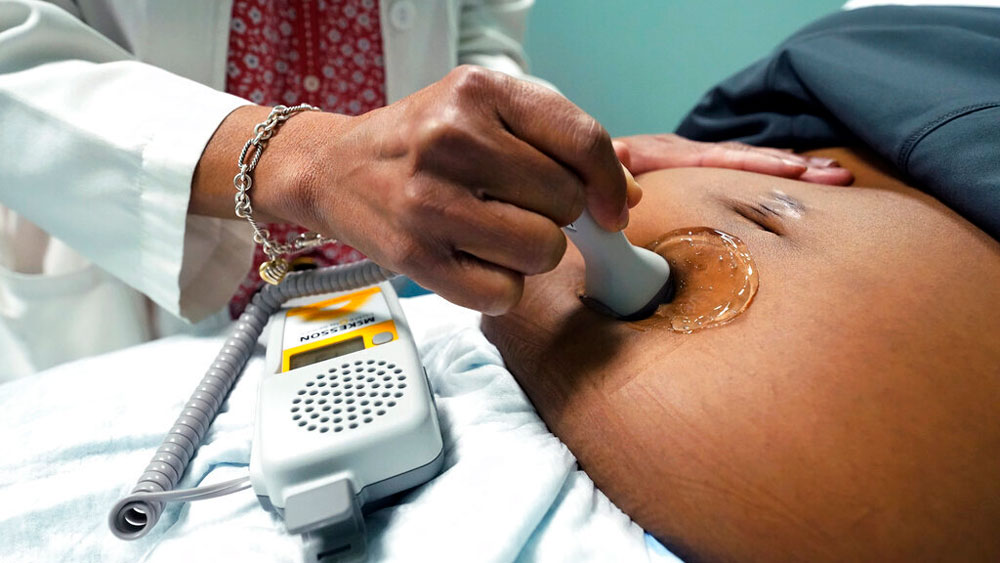 A doctor uses a hand-held Doppler probe on a pregnant woman to measure the heartbeat of the fetus on Dec. 17, 2021, in Jackson, Miss.