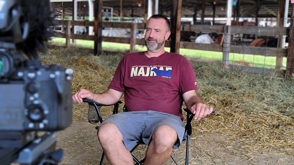 man sits in chair while being interviewed