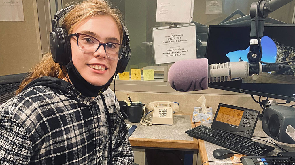 girl sits at microphone in studio