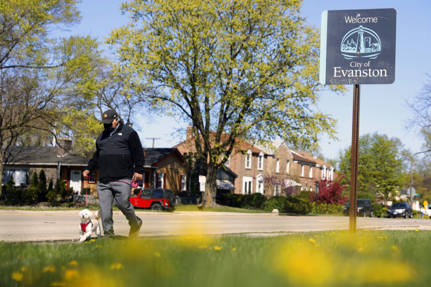 A person walks a dog past a street sign reading 