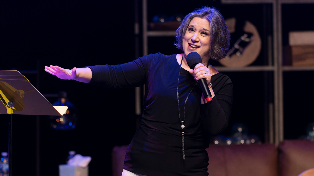 Woman holds microphone with other hand out stretched