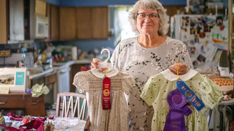 woman stands holds up dresses