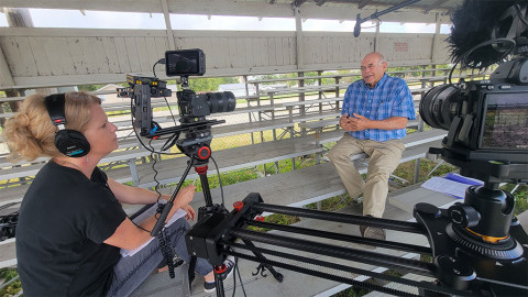 woman interviews man on bleachers