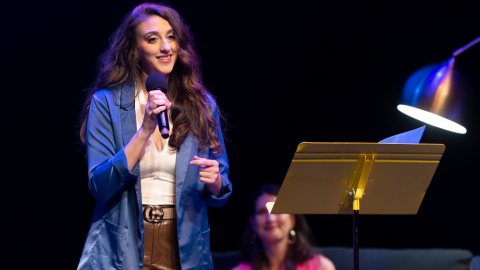 Woman in blue jacket holding a microphone on stage