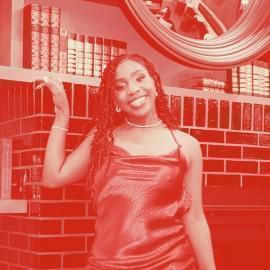 woman in red dress poses in front of fireplace 