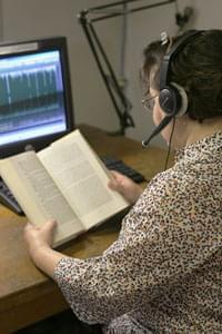 an Illinois Radio Reader volunteer reading a book into a microphone